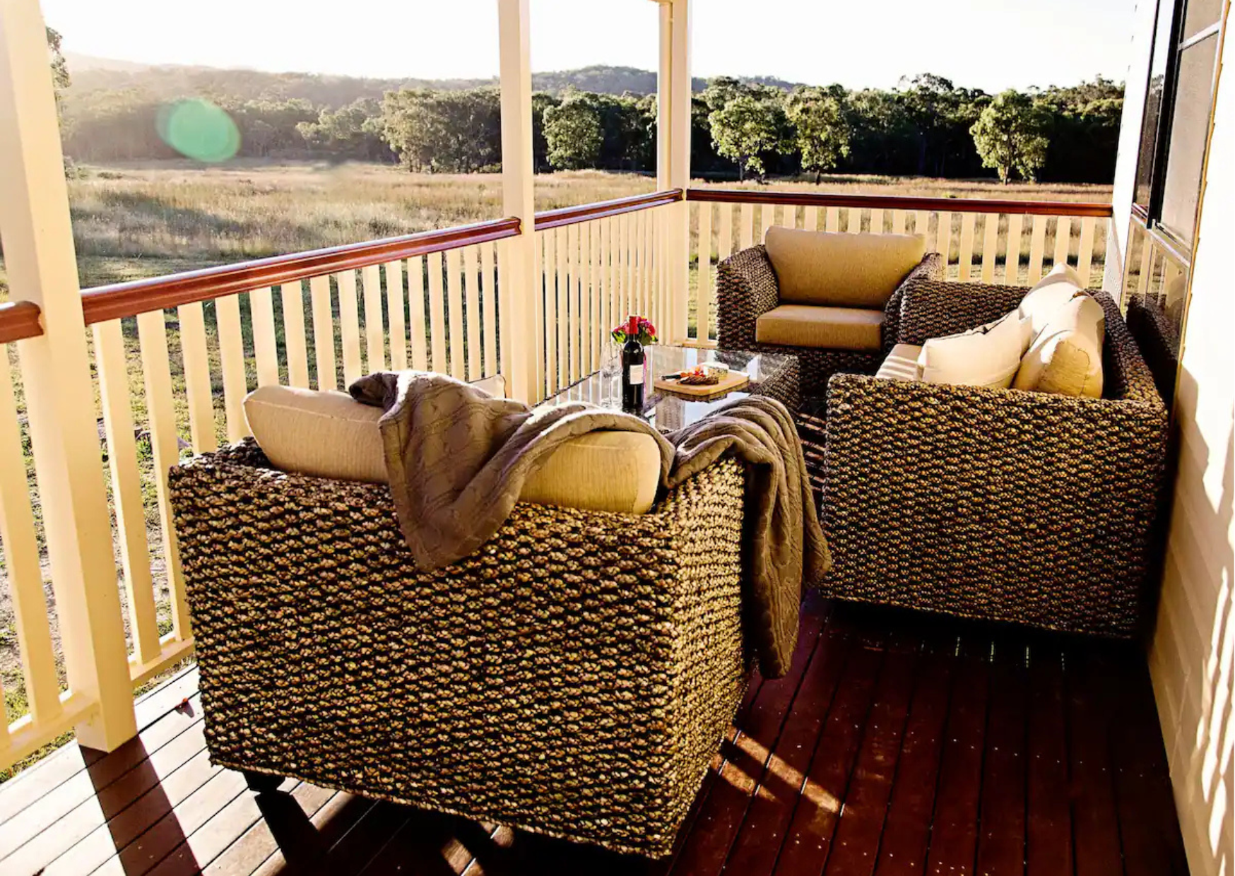 The spacious, covered verandah at The Homestead, with an 8-seater dining table, lounge, and BBQ.
