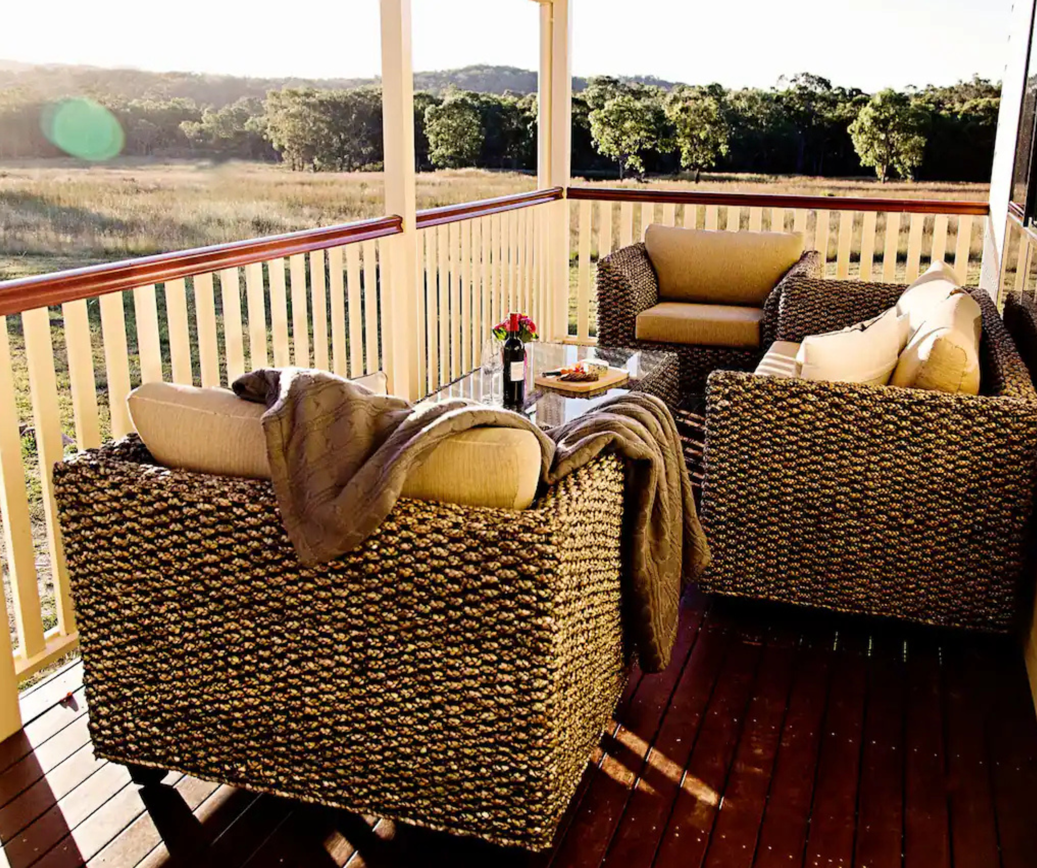 The spacious, covered verandah at The Homestead, with an 8-seater dining table, lounge, and BBQ.
